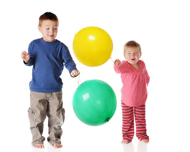 Preschool siblings happily playing together with punchballs.  Isolated on white.
