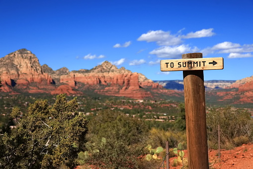 Trail sign pointing to the summit on the Airport Mesa trail in Sedona, Arizona.  Capitol Butte is in the background.