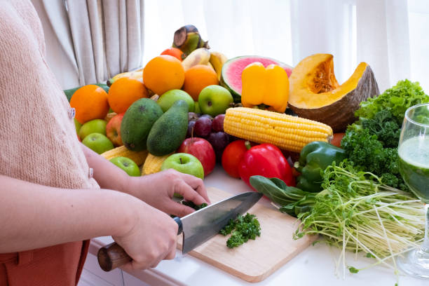 istock a person's hands are visible holding a knife and chopping vegetables on a cutting board with fruit the background is a white curtain 1469047165