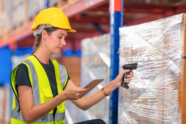 Data storage management arraange the right position.The females warehouse worker check the data on the digital barcode scanner compare with the carton box label in the distribution warehouse. la gestión del almacenamiento de datos arraange la posición correcta. las trabajadoras del almacén verifican los datos en el escáner de código de barras digital en comparación con la etiqueta de la caja de cartón en el almacén de distribución.