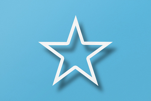 paper cut star shape with light and shadow Placed on a light blue paper background.