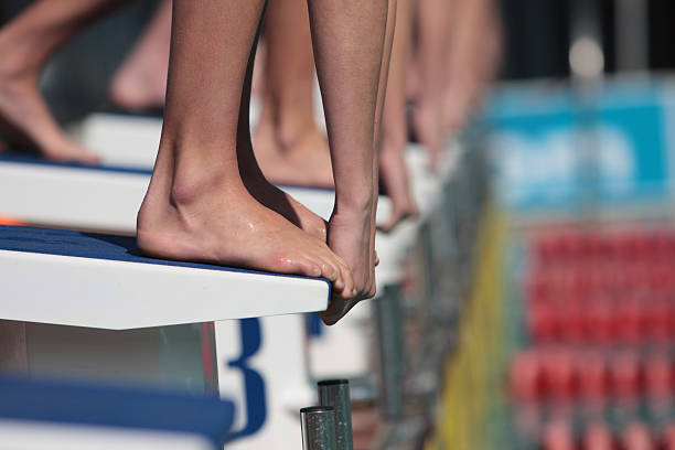 Hands Divers on starting block ready to swim in gala, only hands and feet visable track starting block stock pictures, royalty-free photos & images