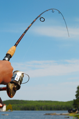 Closeup of a boys hand holding a fishing rod and reel