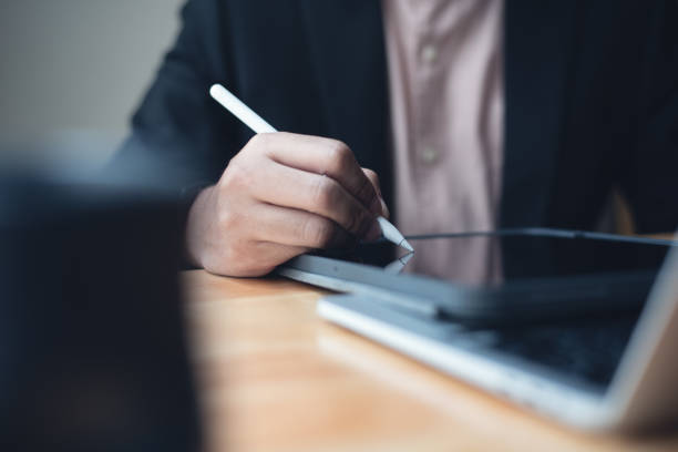 istock E-signing, electronic signature concept. Businessman using stylus pen signing e-document business contract on digital tablet with laptop computer on office table, close up 1469054936