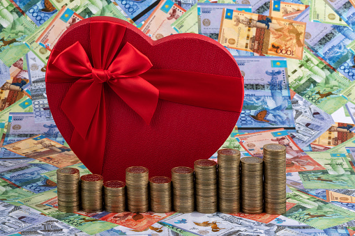 Gift box in the shape of a human heart and Kazakhstani currency - tenge