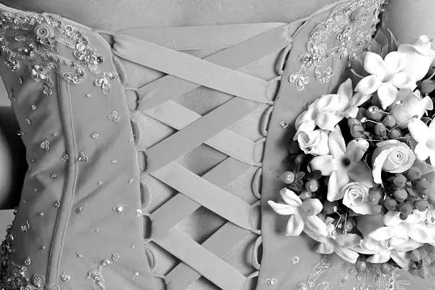 Back of a beautiful wedding dress with bouquet in hand.