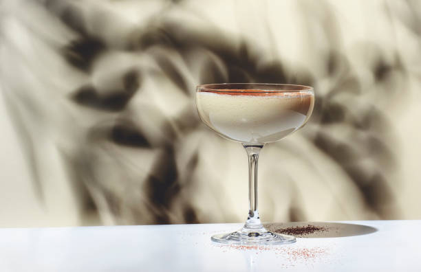 brandy alexander alcoholic cocktail drink with cognac, cocoa liquor, cream, nutmeg and ice. light beige background, hard light, shadow pattern - hot drink fotos imagens e fotografias de stock