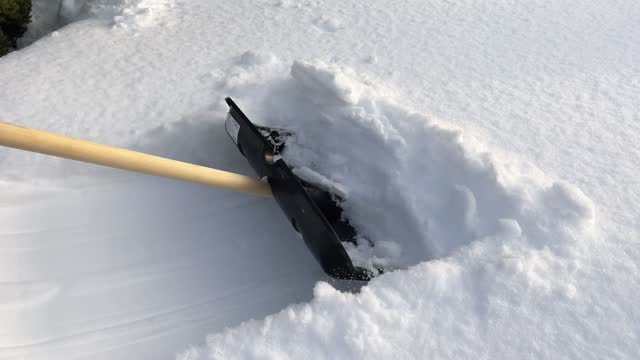 A man cleans the path from snow with a shovel. Snow removal. High quality 4k footage with slow motion.
