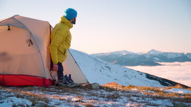Male hiker camps out in winter, on mountain ridge