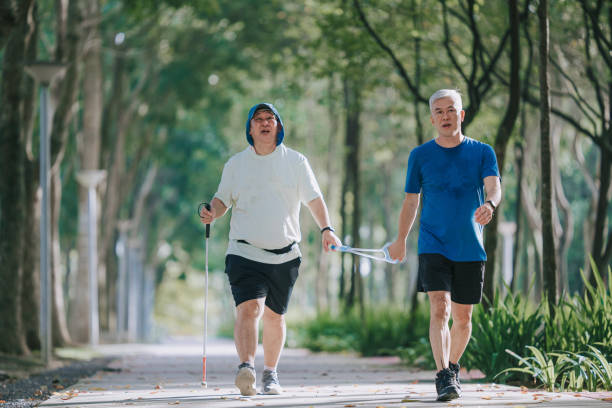 zbliżenie na azjatyckiego chińczyka niedowidzącego dojrzałego mężczyznę trzymającego uwięzi biegowe w publicznym parku z przewodnikiem - blind trust zdjęcia i obrazy z banku zdjęć