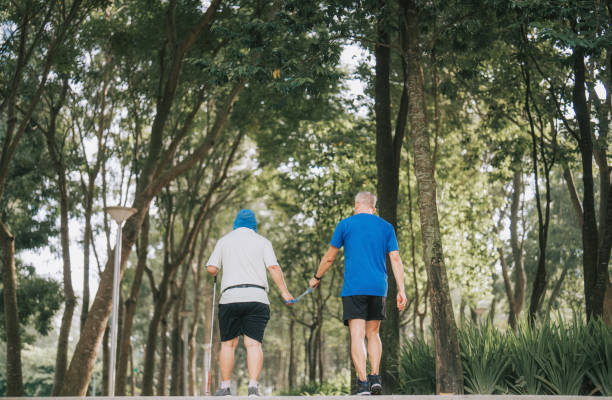 istock Asian Chinese visually impaired mature man holding running  tether in public park with guide runner 1469077012