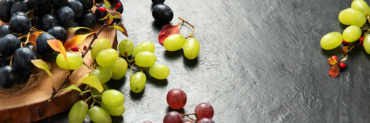 Green and black grapes on a wooden plate. Top view. Panorama with copy space.