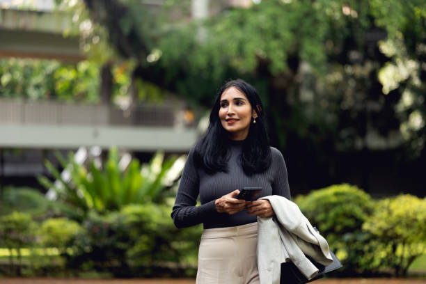 istock Indian businesswoman walking and using her mobile phone 1469082173