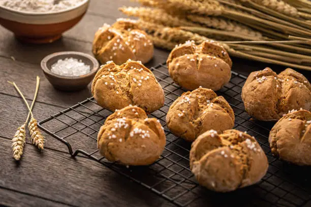 Homemade spelt bread rolls with salt on wooden background