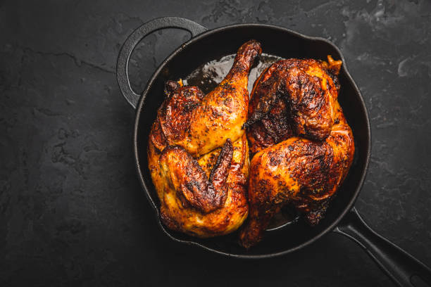 Roasted half chicken in pan on black background Roasted half chicken in pan on black background halved stock pictures, royalty-free photos & images