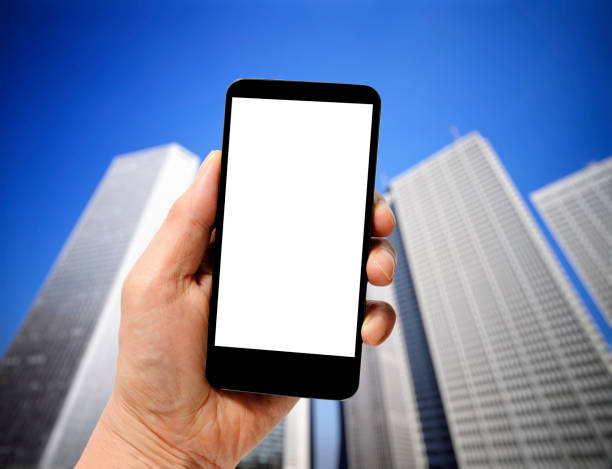 Close-up of hand holding a smartphone with blank screen against skyscrapers.