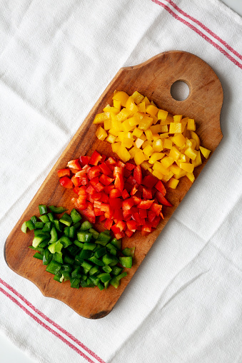 Chopped Fresh Colored Peppers on a Rustic Wooden Board, top view. Flat lay, overhead, from above.