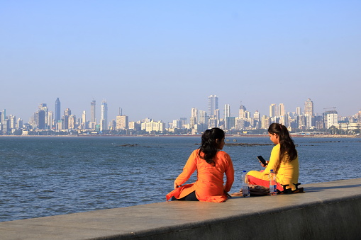 December 20 2022 - Mumbai, Maharashtra in India: People enjoy the afternoon in front of the Mumbai skyline view from Marine Drive