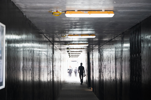 Unrecognised man walking in a dim tunnel in London, concept use