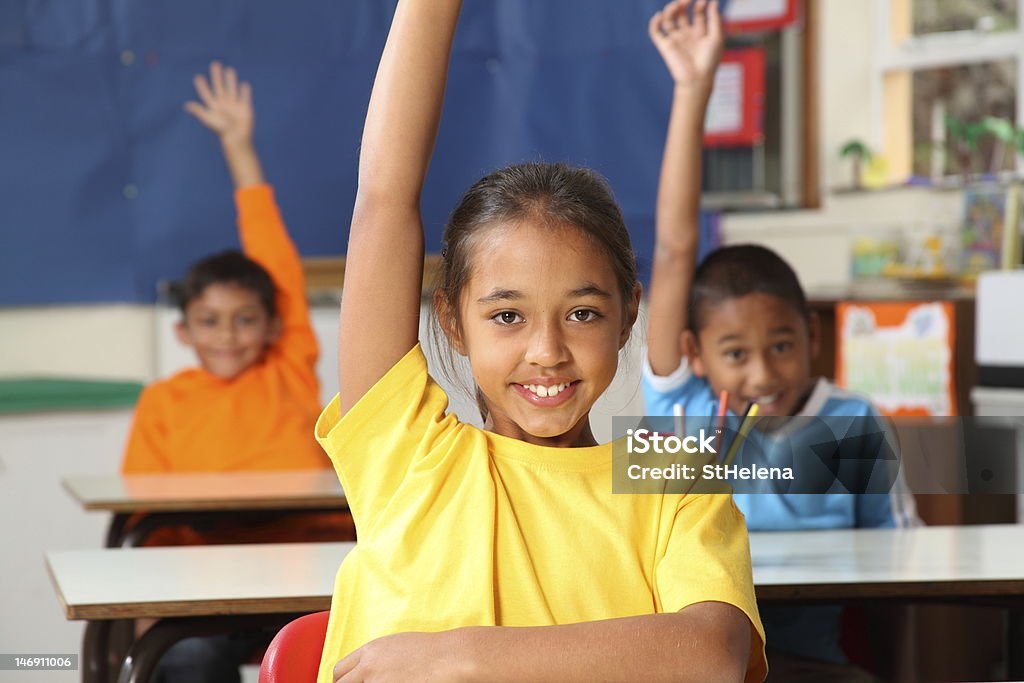 Three primary school children hands raised in class Three cheerful young primary school children indicating they know the answer with hands raised in class - Canon 5D MKII Hand Raised Stock Photo