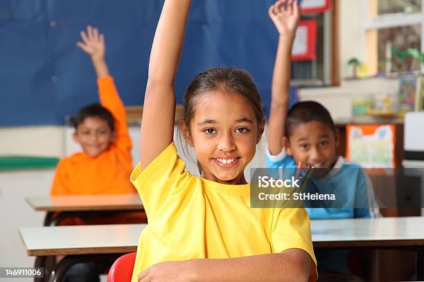 Três Crianças Das Escolas Primárias As Mãos Levantadas Em Class Turma - Fotografias de stock e mais imagens de Mão Levantada