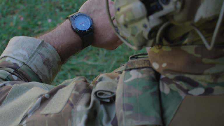 Close-up unrecognizable male soldier in camouflage uniforms getting ready for military exercises or battle. Detailed shot of military man checking time, looking at watch. Ukrainian russian war