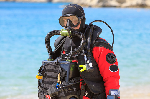 Technical  Diving with Military Rebreather.  Water sports. Handsome scuba diver, men ready to go scuba diving. Dressed in a scuba diving dry suit  Sporting men. Beautiful blue sea in the background.