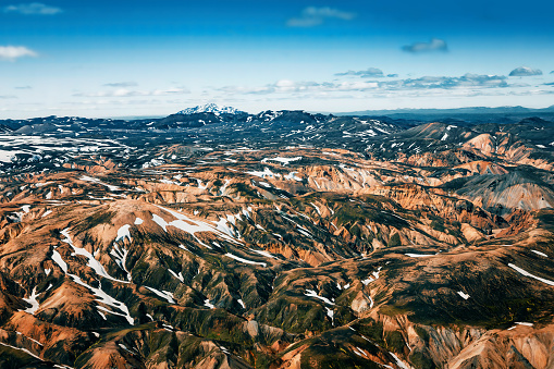 Aerial capture of the colorful hills and mountains with their sparse vegetation and snow caps in the Landmannalaugar area in south-west Iceland during summer.