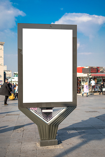 Vertical blank billboard on the city square in background buildings and road with cars mock up