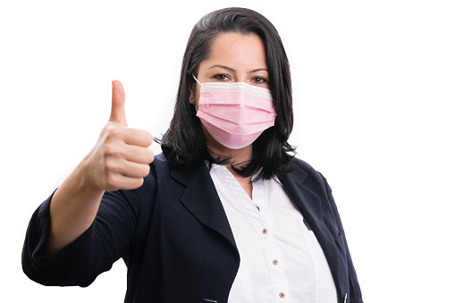 Adult entrepreneur woman model wearing surgical or medical disposable protective mask making thumb up gesture as like covid19 sars flu pandemic isolated on white background