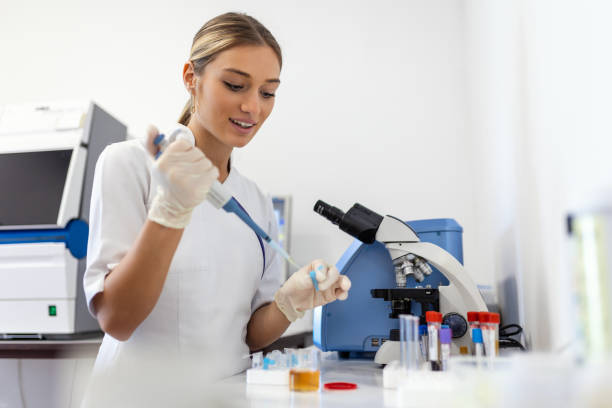 biologa donna che utilizza micro pipetta con provetta e becher per esperimenti in laboratorio scientifico. specialista di biochimica che lavora con attrezzature di laboratorio e vetreria per lo sviluppo. - test tube biologist laboratory beaker foto e immagini stock