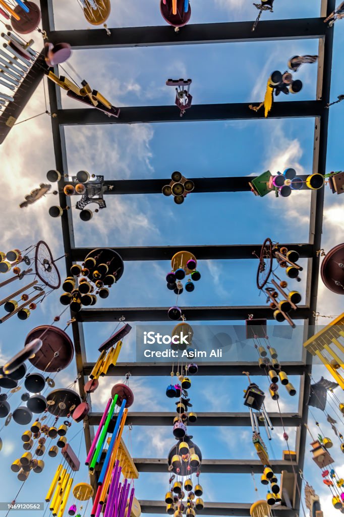 Wind chimes of deferent pattern, material and designs hanging high up on a wooden structure Wind chimes of deferent pattern, material and designs hanging high up on a wooden structure with the sky in background Motivation Stock Photo