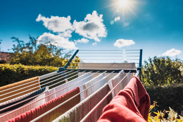 secado de ropa mojada ecológicamente al sol en un tendedero durante el verano después de lavar la ropa - shirt hanger hanging blue fotografías e imágenes de stock