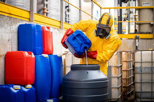 Trabajador químico o tecnólogo con traje de protección amarillo y máscara de gas que fabrica ácido sulfúrico para la industria. photo