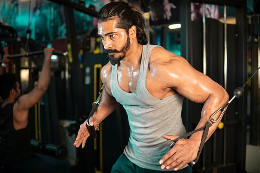 Serious sporty muscular young man training with trx suspension in the gym.