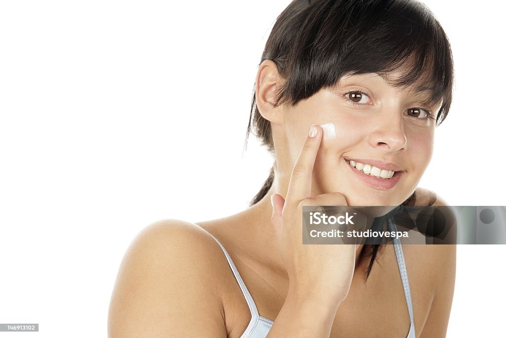 A young brunette girl applying a cream to her cheek Young woman applying face cream Applying Stock Photo