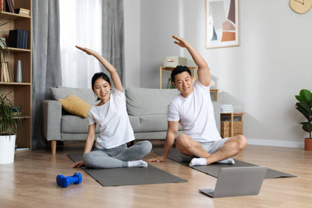 istock Sporty asian man and woman exercising at home, using notebook 1469136921