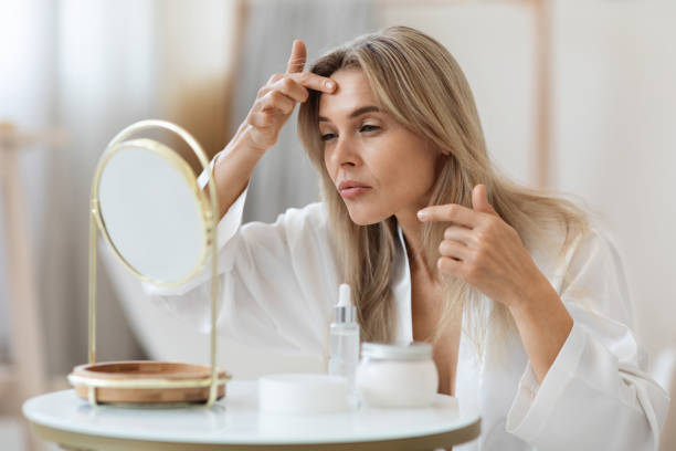 Middle aged woman in bathrobe looking at mirror