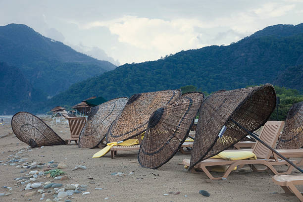 Damaged Umbrellas on Beach in front of Taurus Mountains Damaged Umbrellas on Beach in front of Taurus Mountains - Cirali, Turkey, Asia cirali stock pictures, royalty-free photos & images