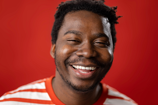 Studio shot of happy African American man with toothy smile looking at camera.