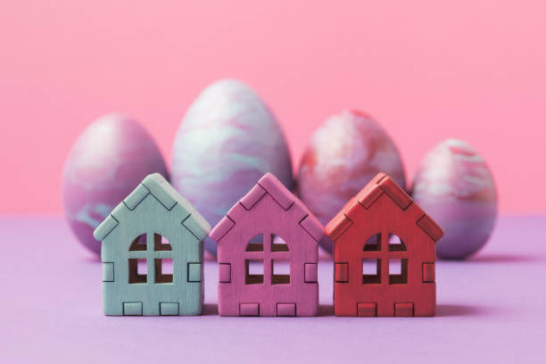 istock Three painted toy houses over decorated Easter eggs. Selective focus. Easter holiday greeting concept 1469139021