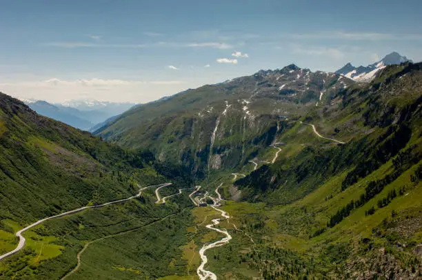 A wide view of a section of the Furka Pass in the Swiss Alps on a sunny day.
