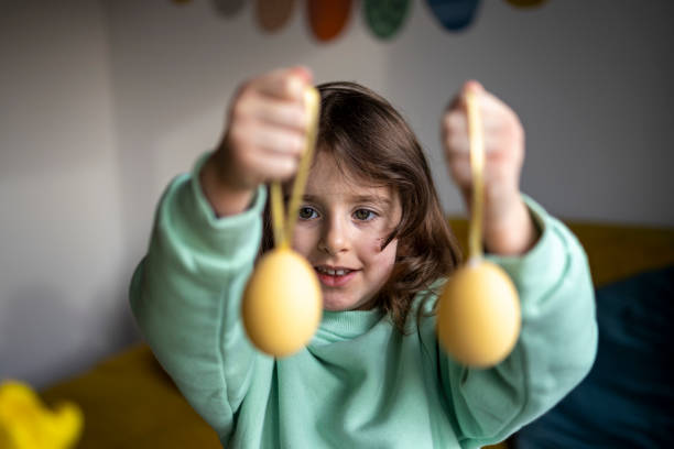 istock Little smiling girl showing two yellow Easter eggs at home 1469140838