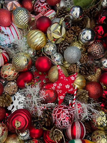 Stock photo showing close-up, elevated view of pile of Christmas ornaments in red and gold colour scheme for decorating a Christmas tree.
