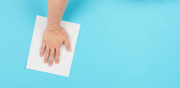 istock Hand is wiping and hold white paper tissue on blue background. 1469143860