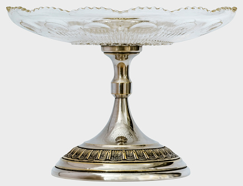 Studio shot of vintage glass cake stand plate with embellished silver pedestal, isolated on white background, side view.