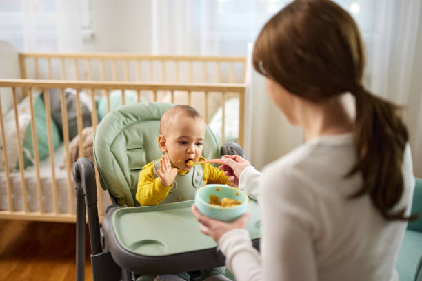istock Mother spoon feeding her baby son at home 1469145716