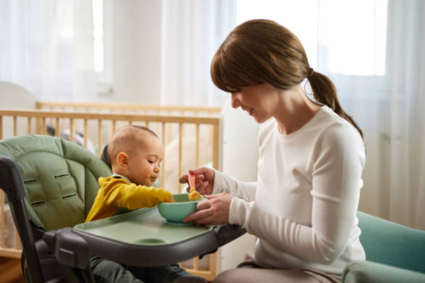 istock Mother spoon feeding her baby son at home 1469145758