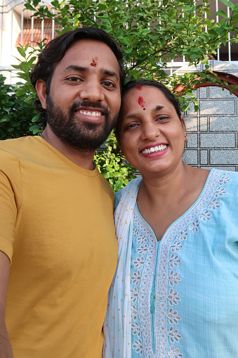 Stock photo showing an Indian women standing in a garden wearing traditional Kurta and Salwar Kameez with her brother taking a selfie.