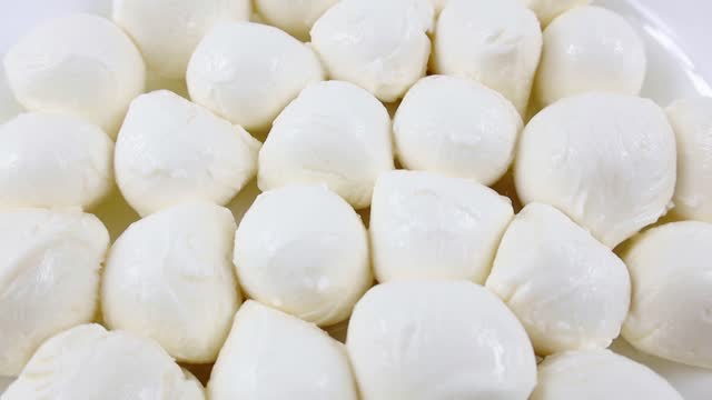 Many fresh white mozzarella cheese balls rotation close up